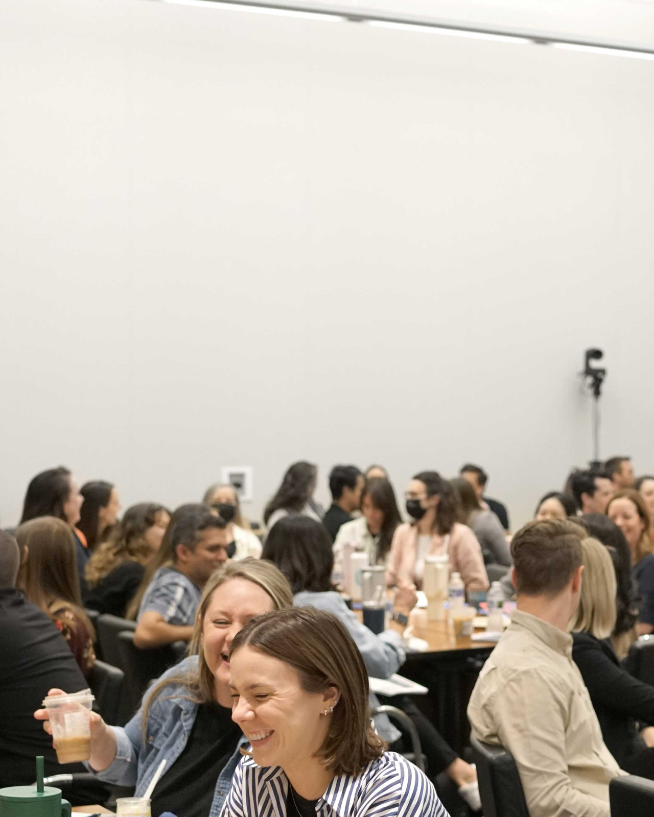 A crowd of event attendees sitting at tables together during a workshop