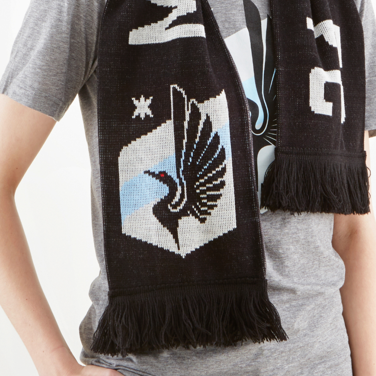 Merch items for MNUFC, including a t-shirt and knit scarf that features the team crest.