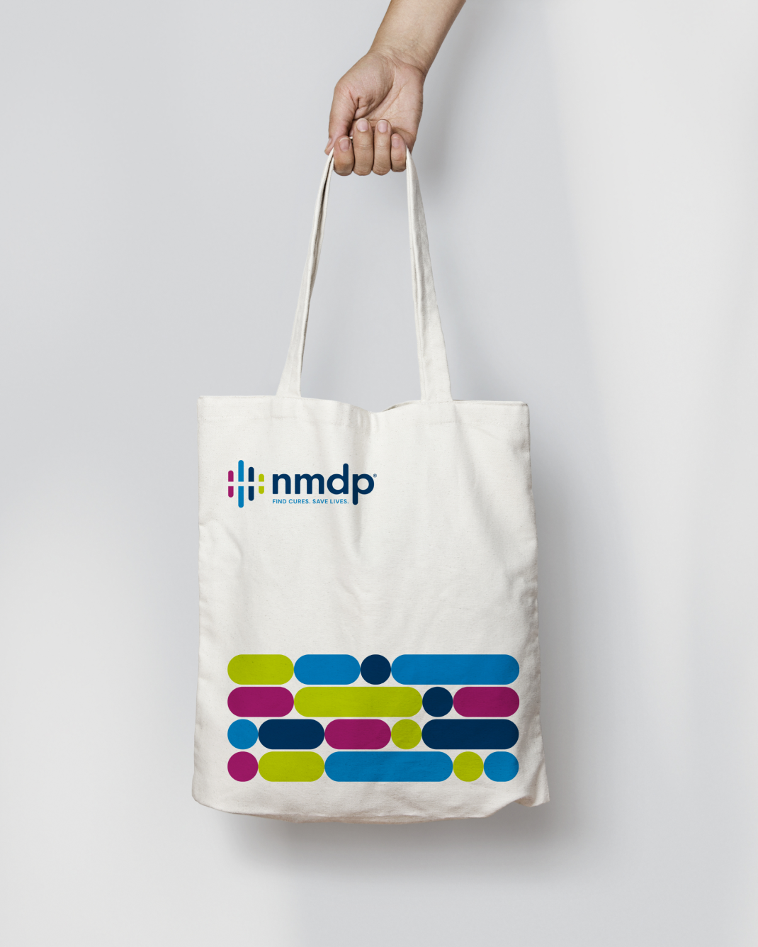 A white tote bag with the NMDP logo and graphic identity elements printed on it.