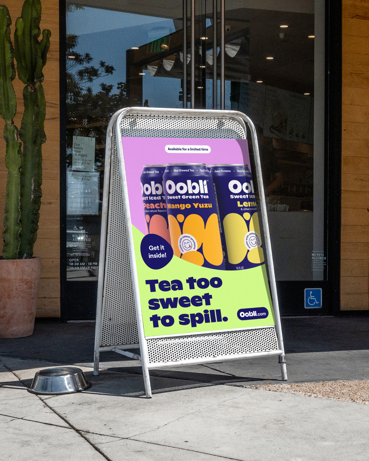 A tent sign outside of a store entrance, advertising that the store sells Oobli’s sweet tea, with the message “Tea too sweet to spill.”