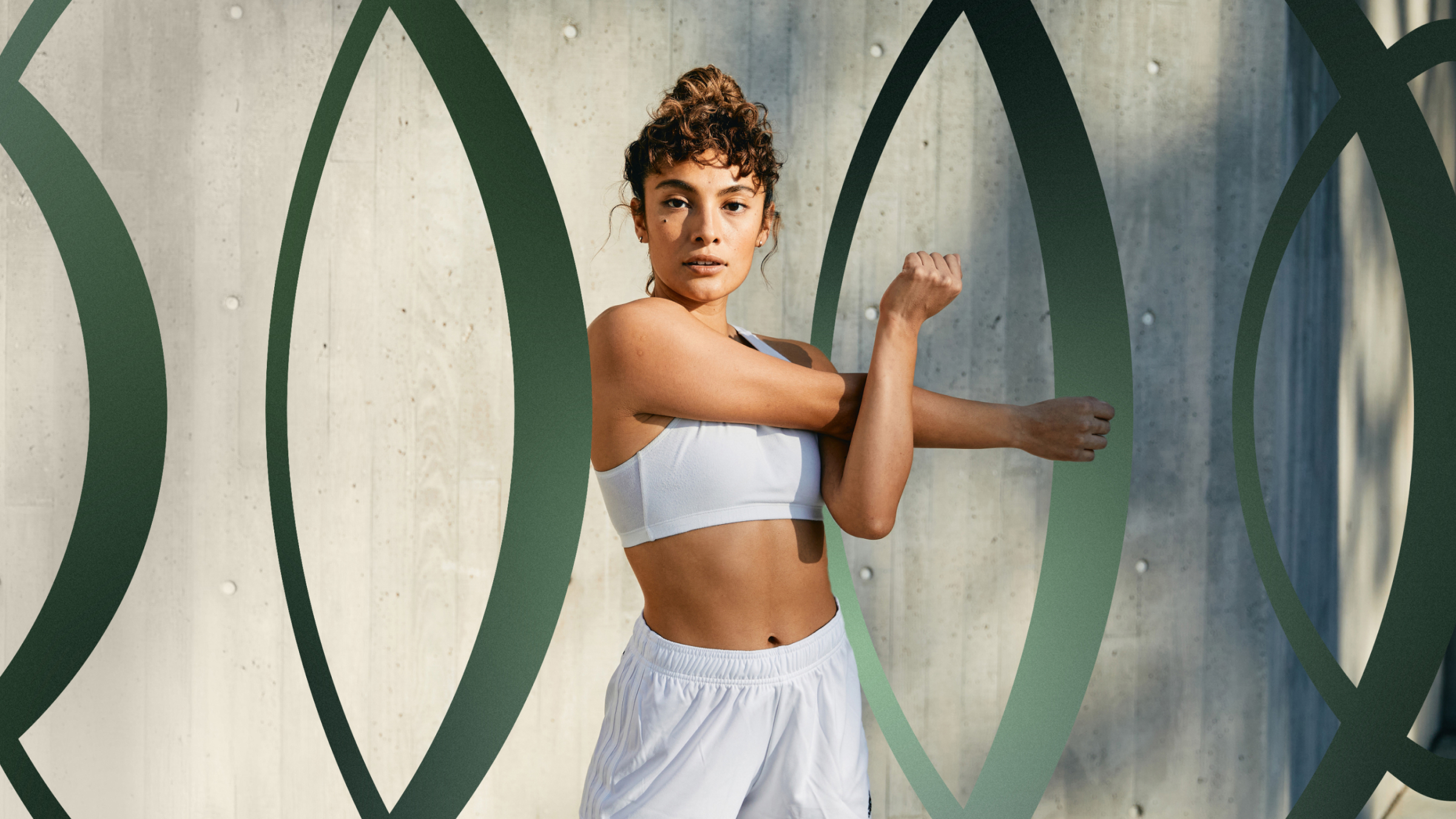 Athletic woman in front of concrete wall with Packers Athletic Club Logo