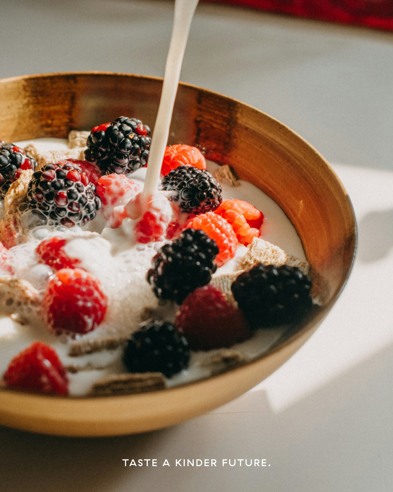 Milk pouring into a bowl of granola and berries